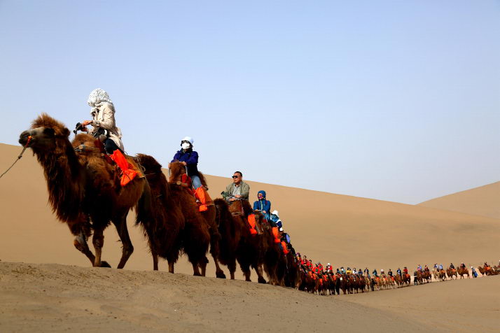 Travelers are touring the Mingsha Mountain and the Yueya Lake near Dunhuang City of Gansu Province on April 30 (XINHUA)